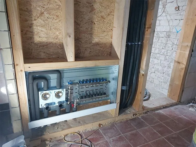 Verteiler einer Fußbodenheizung im Holzständerwerk eines Rohbaus