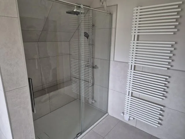 Glasdusche mit Handtuchheizkörper und großformatigen Fliesen