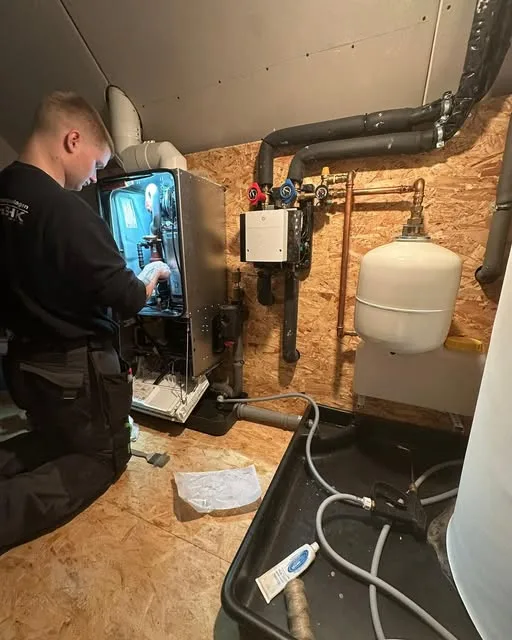 Monteur von hinten bei der Arbeit an einem Wärmeerzeuger im Technikraum